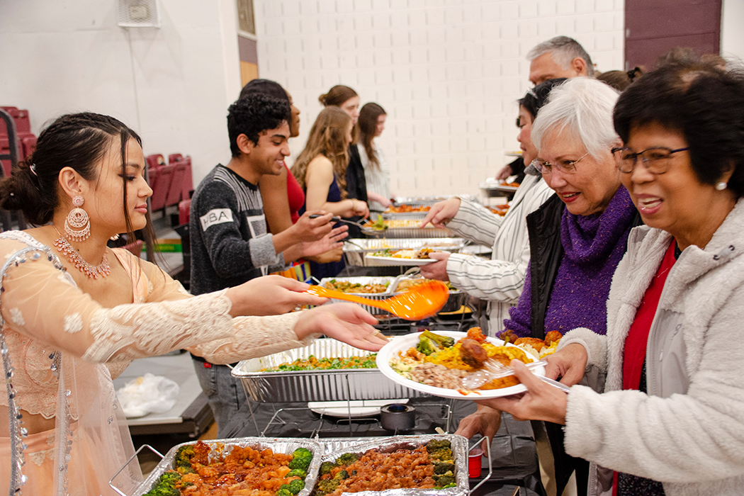 Photo of students serving a meal to guests at the International Dinner