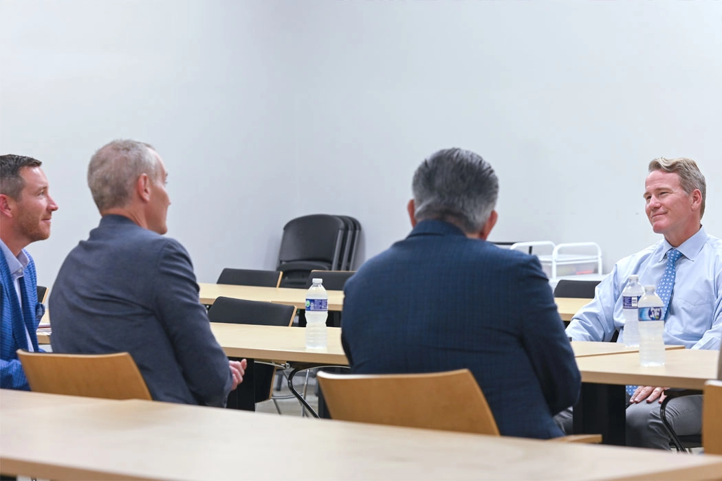 Photo of a group of men seated at a table having a discussion.