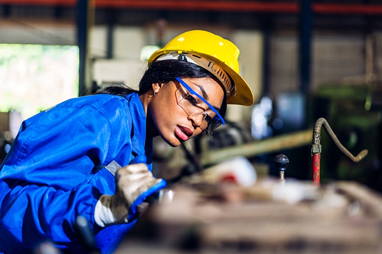 photo of a woman in a manufacturing job assessing a piece of equipment